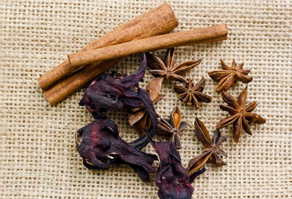 Cinnamon sticks, dry hibiscus flowers and anise stars on a burlap