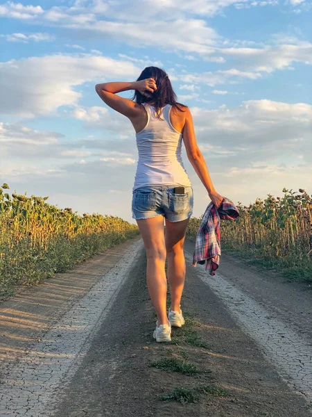 Ung Flicka Jeansshorts Och Vit Shirt Går Längs Landsvägen Utsikt Stockfoto