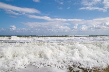Güneşli bir yaz gününde kumlu plajda dalgalar