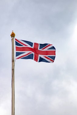 Gri bir İngiliz gökyüzüne karşı uzun bir bayrak direğinde İngiliz bayrağı