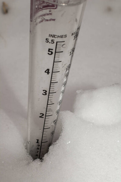 Крупный план измерительного датчика, стоящего в 2 дюйма снега
