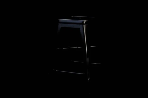 Black metal bar stool with step on black background. Loft chair. 3d render