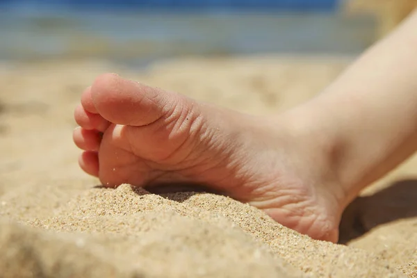 Benen van een kind op het zand op het strand — Stockfoto
