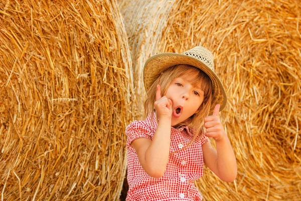 Criança feliz em um campo com fardos colheita no outono — Fotografia de Stock