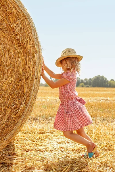 Criança feliz em um campo com fardos colheita no outono — Fotografia de Stock