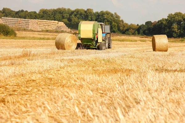 Egy traktor, az őszi háttérben mező széna bálák — Stock Fotó