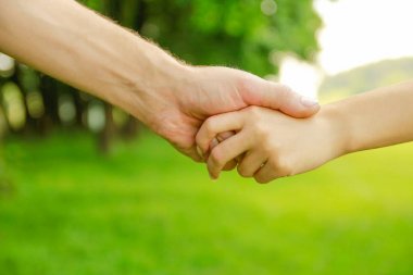 Mutlu aile ve çocuk parkta el ele tutuşuyor.