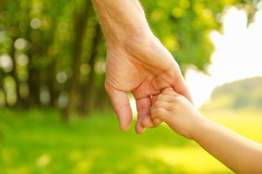 Mutlu aile ve çocuk parkta el ele tutuşuyor.