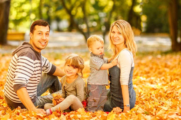 Happy family lying on the autumn leaves in the park — Stock Photo, Image