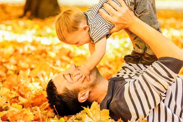 Padres felices con un niño jugando en un parque en otoño — Foto de Stock