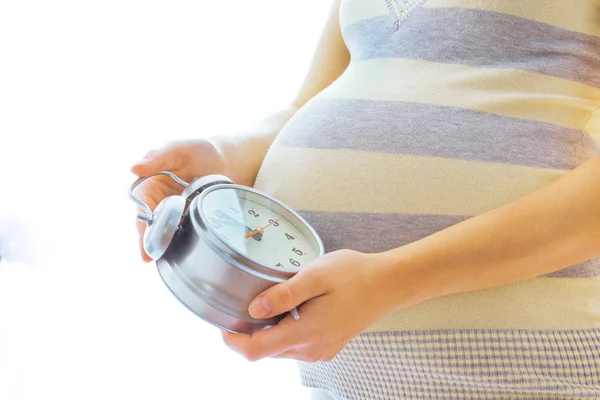 Mooie jong zwanger meisje op een witte achtergrond met alarm c — Stockfoto