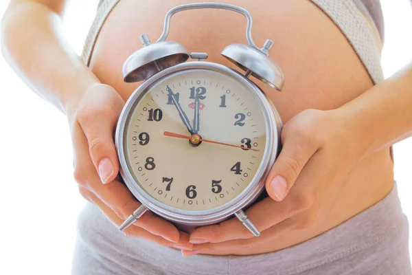 Hermosa joven embarazada sobre un fondo blanco con alarma c — Foto de Stock