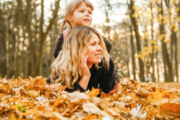 Lycklig kvinna med en bebis på höstlöv i naturen — Stockfoto