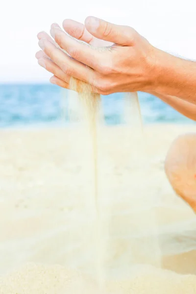 happy guy pours sand from the sea of hands