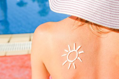 Güneşli bir kız havuzda sırtüstü yatıyor.