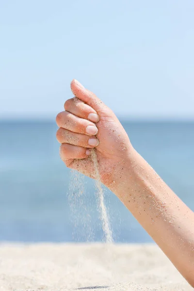 Mão sobre o mar derrama areia sobre a natureza — Fotografia de Stock