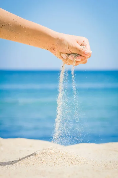 Руки посыпают песком у моря — стоковое фото