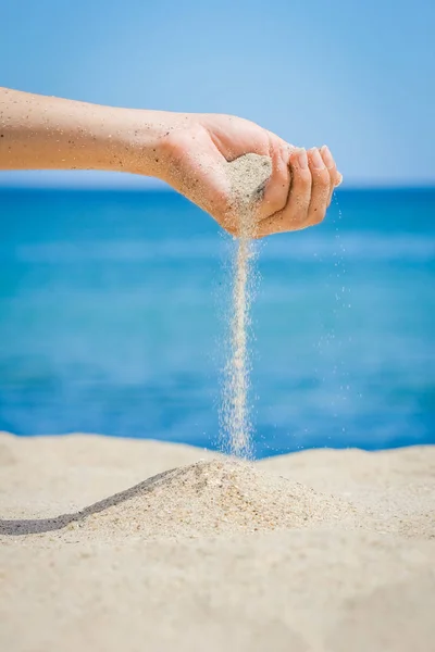 손으로 모래를 바다에 쏟고 있다 — 스톡 사진