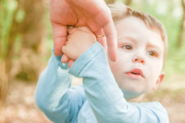 幸せな背景を持つ子供の手を握っている親は — ストック写真