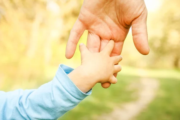 De ouder die de hand van het kind met een gelukkige achtergrond vasthoudt — Stockfoto