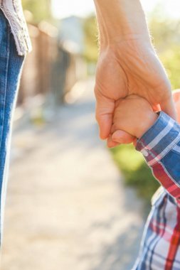 Mutlu bir geçmişi olan çocuğun elini tutan ebeveyn.