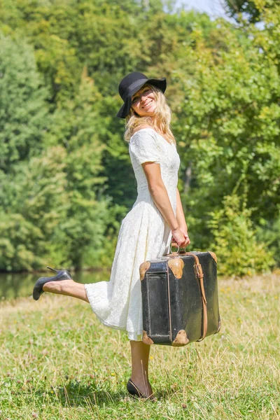 Glückliches Mädchen mit einem Koffer im Freien im Park — Stockfoto