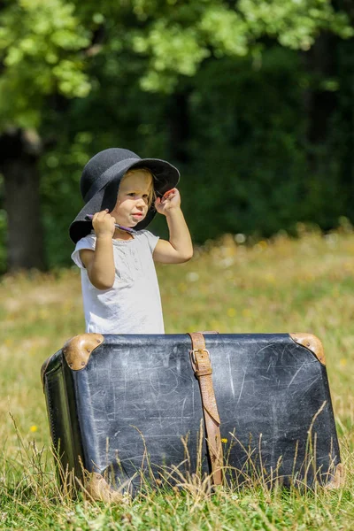 Bébé fille heureuse avec une valise à l'extérieur au parc — Photo
