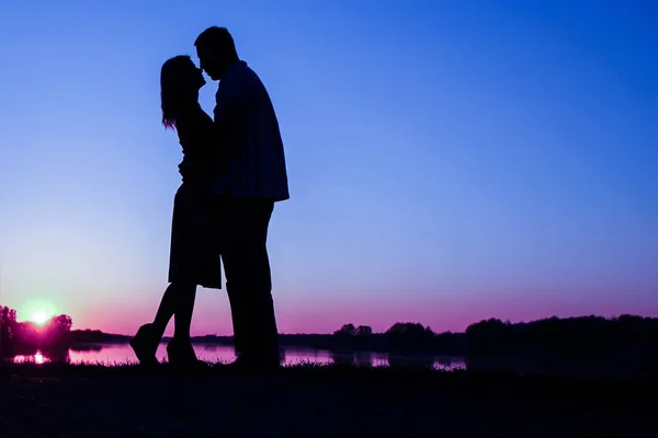 Счастливая пара силуэт против заката романтики — стоковое фото