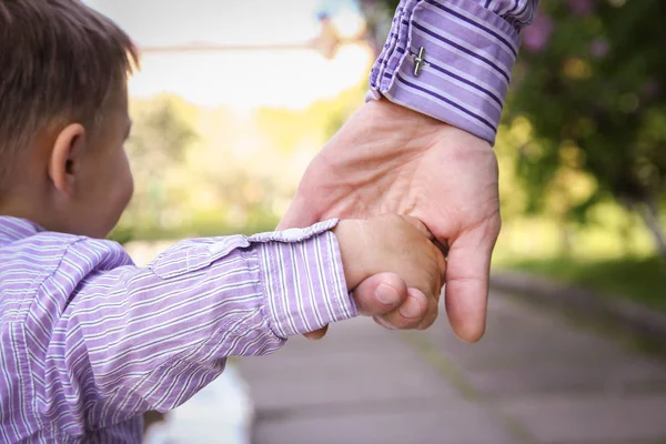 De ouder die de hand van het kind met een gelukkige achtergrond vasthoudt — Stockfoto