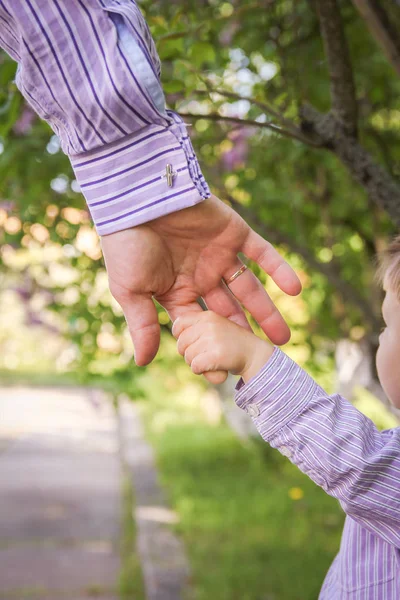 De ouder die de hand van het kind met een gelukkige achtergrond vasthoudt — Stockfoto