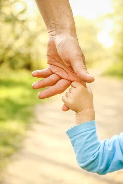 De ouder die de hand van het kind met een gelukkige achtergrond vasthoudt — Stockfoto