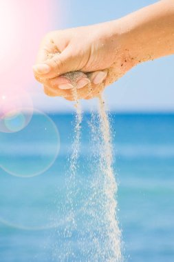 Denizin kenarından kumlar dökülüyor