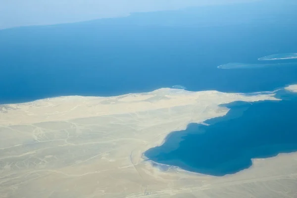 Земля и море из иллюминатора самолета — стоковое фото