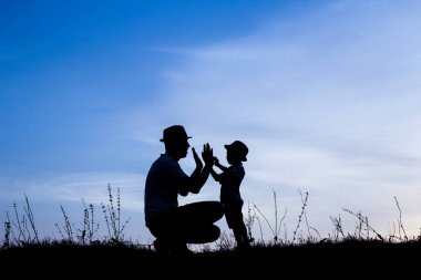 Çocuklu mutlu bir ebeveyn yaz siluetinde oynuyor.