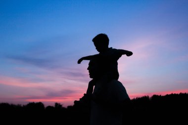 Çocuklu mutlu bir ebeveyn yaz siluetinde oynuyor.