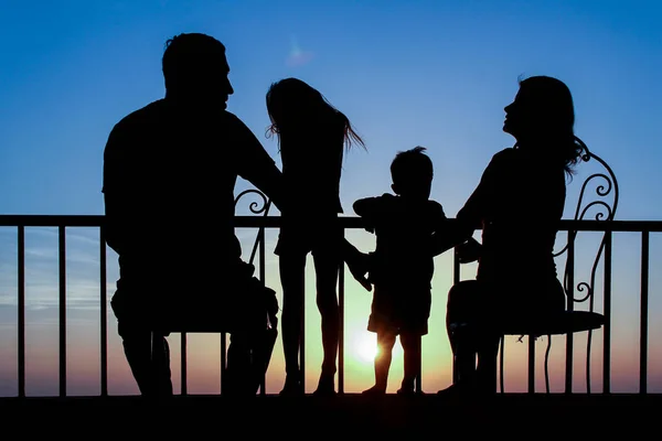 Familia feliz en el amanecer del fondo de la silueta del mar —  Fotos de Stock