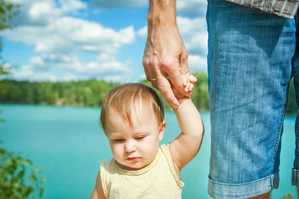 Mani di un genitore e di un bambino nella natura in un parco in riva al mare — Foto Stock