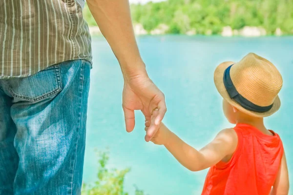 Manos de un padre y un niño en la naturaleza en un parque junto al mar —  Fotos de Stock