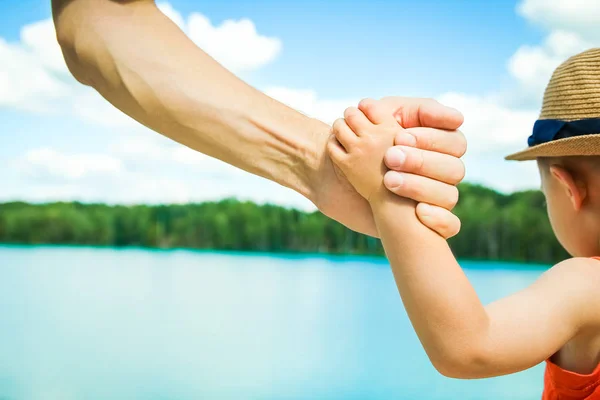 Händerna på en förälder och barn i naturen i en park vid havet — Stockfoto