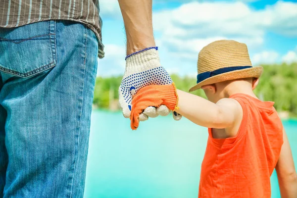 Manos de un padre y un niño en la naturaleza en un parque junto al mar —  Fotos de Stock