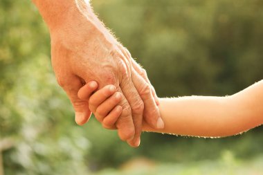 Mutlu bir geçmişi olan çocuğun elini tutan ebeveyn.