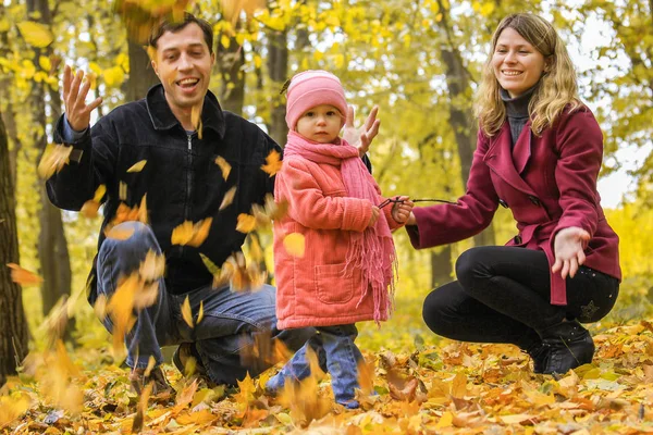 Família feliz que joga nas folhas de outono em um parque na natur — Fotografia de Stock