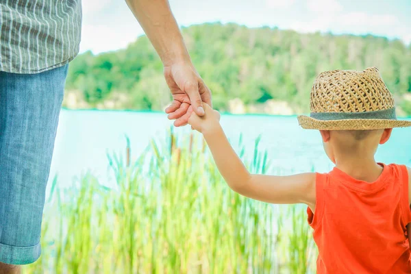 Manos de un padre y un niño en la naturaleza en un parque junto al mar —  Fotos de Stock