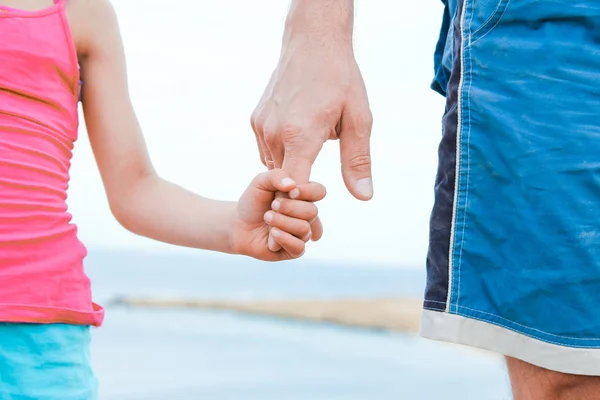Krásné ruce rodiče a dítěte na mořském pozadí — Stock fotografie
