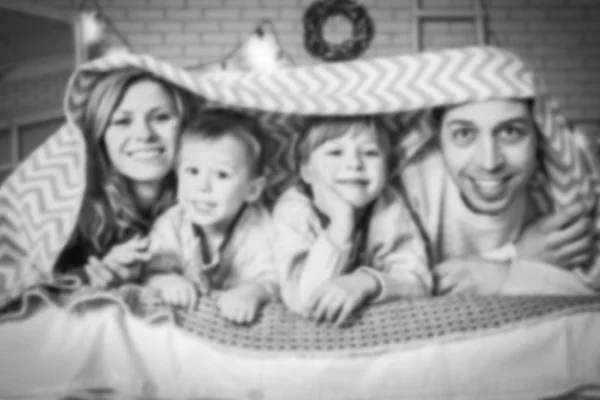 Familia feliz acostada bajo las sábanas en casa — Foto de Stock