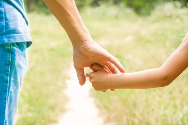 Orang tua memegang tangan anak dengan latar belakang bahagia — Stok Foto