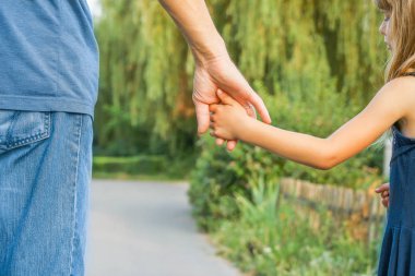 Mutlu bir geçmişi olan çocuğun elini tutan ebeveyn.