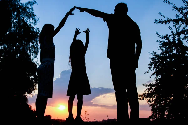 Família feliz juntos na silhueta do pôr do sol — Fotografia de Stock