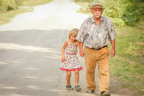 Glad farfar promenader med ett barn på väg till parken — Stockfoto
