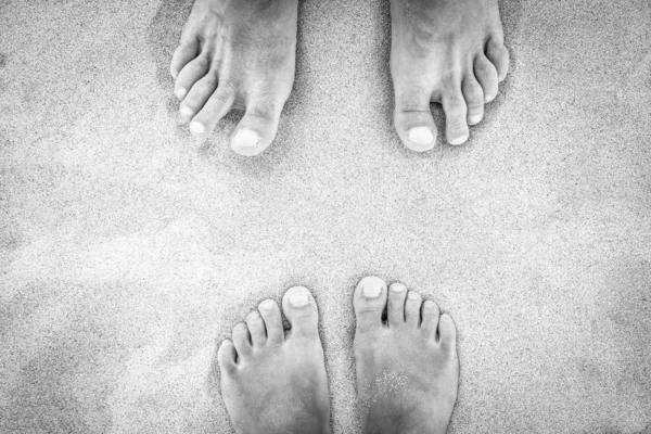 Hermosas piernas en la arena cerca de la orilla del mar en el fondo de la naturaleza —  Fotos de Stock